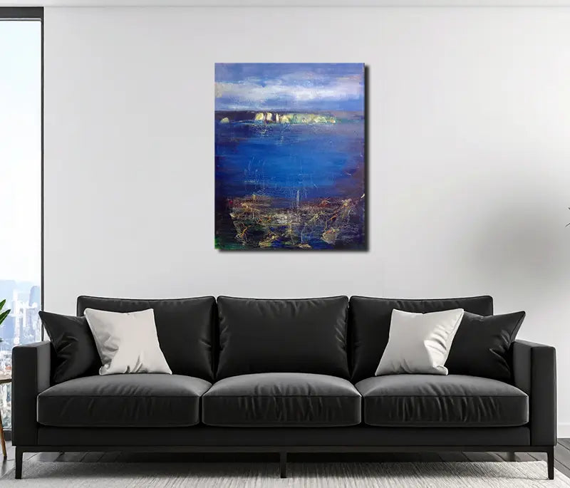 Eine Küstenlandschaft mit heller Steilküste am Horizont, Himmel mit Wolken, an heller Wand hängend mit dunklem Sofa