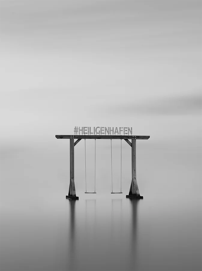 Der Schriftzug Heiligenhafen auf einer Schaukel im Wasser, s/w Langzeitbelichtung, 120 x 90 cm, Thomas Dalecki, Kunst-Direkt.de
