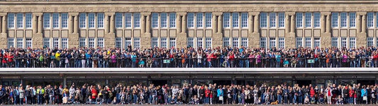 eine große Menschenmenge steht an einem Geländer und wartet auf etwas., Panoramabild