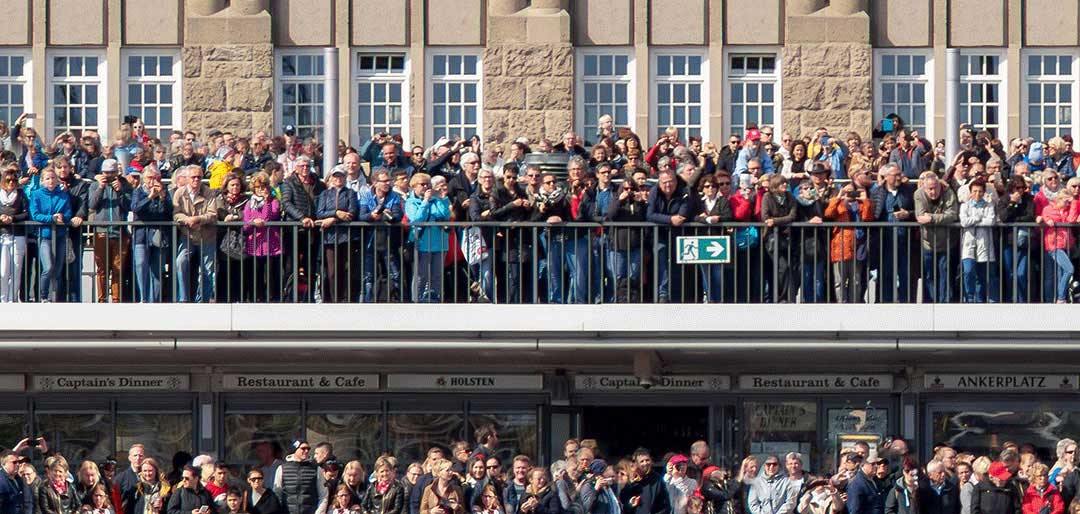 eine große Menschenmenge steht an einem Geländer und wartet auf etwas., Panoramabild, Details der Menschen