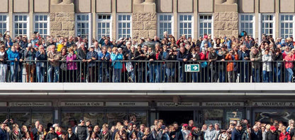 eine große Menschenmenge steht an einem Geländer und wartet auf etwas., Panoramabild, Details der Menschen