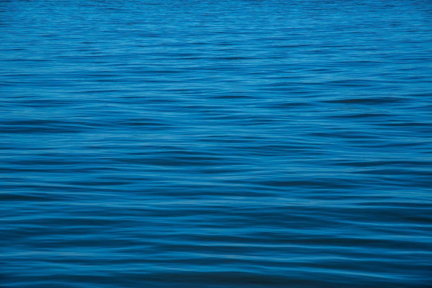 Die Meeresoberfläche mit Wellen, kein Himmel, nur blaues Wasser mit Wellen